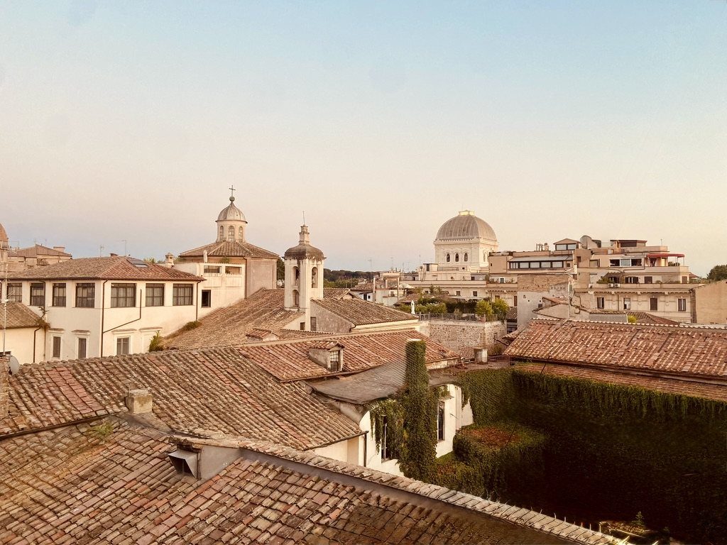 The rooftops of the historic centre at golden hour, with the dome of the Great Synagogue on the horizon