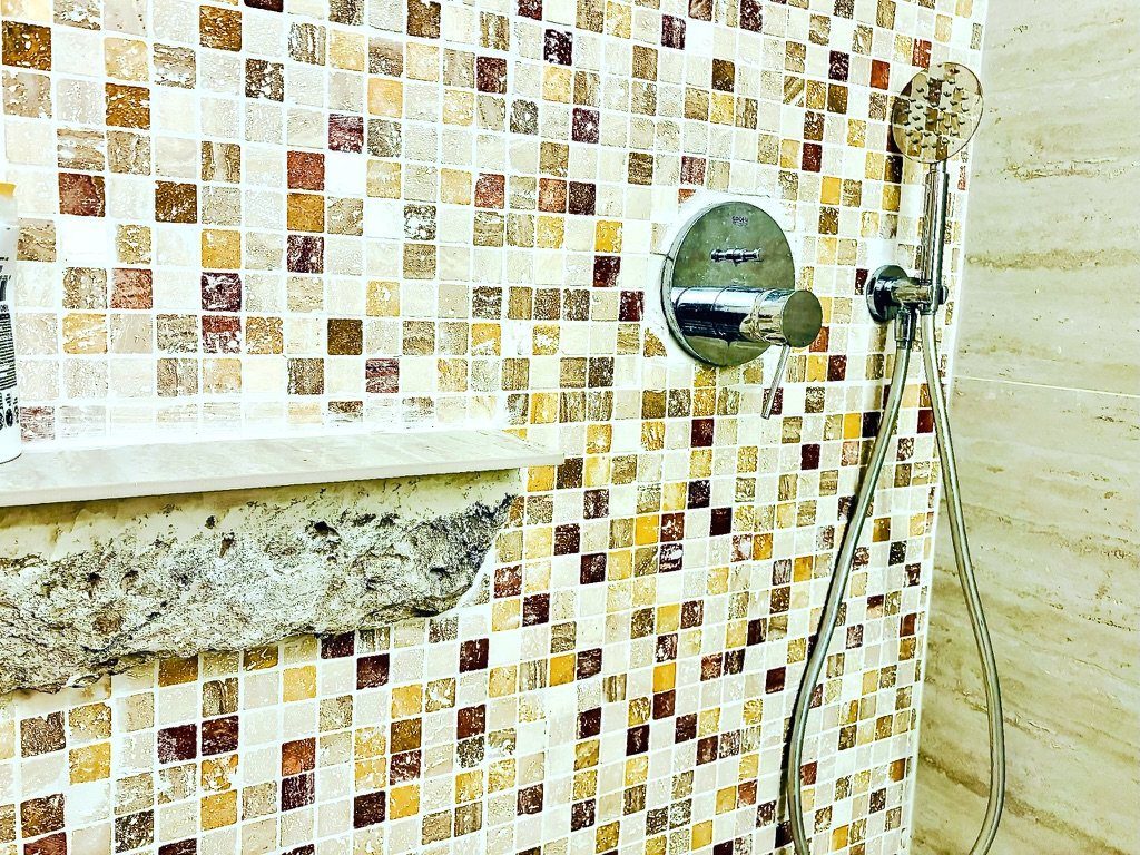 Close-up of the shower’s mosaic tiles, rain showerhead and hand shower