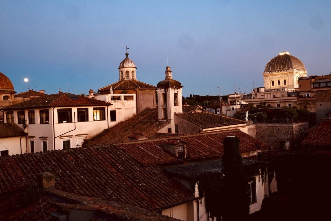 The rooftops at dusk, with the moon rising beside the dome of the Great Synagogue