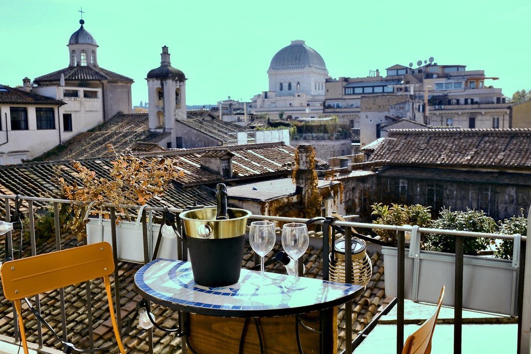 The balcony table set with a bottle on ice and two glasses, with the dome of the Great Synagogue behind the rooftops