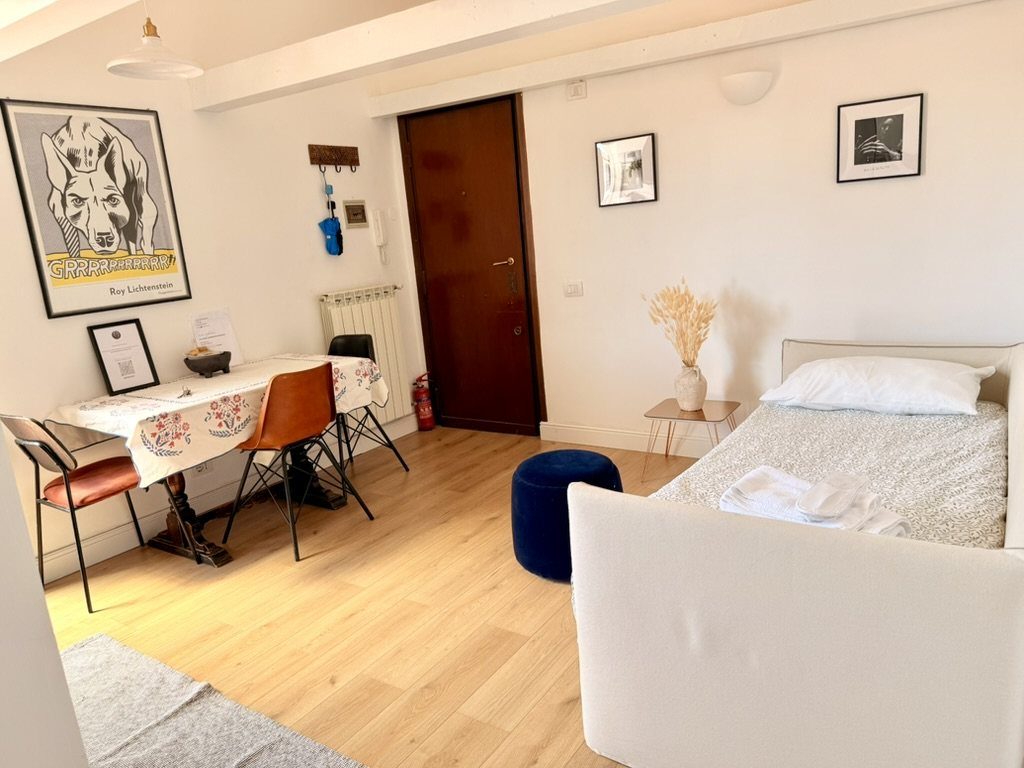 The living room, with the dining table, the entrance door and the sofa bed