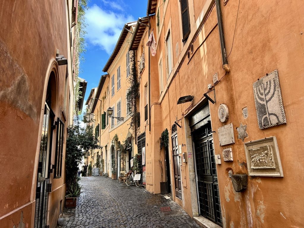 A cobbled lane in the Jewish Ghetto, with a menorah relief and a Star of David on the wall